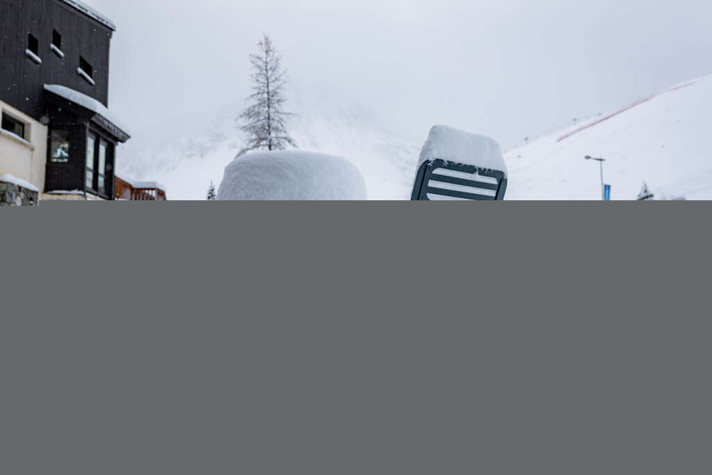 Table and chair covered in fresh snow in Tignes